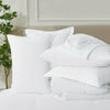 Neatly arranged white bedding set with pillows and duvet in a bright modern bedroom