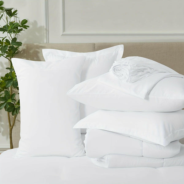Neatly arranged white bedding set with pillows and duvet in a bright modern bedroom